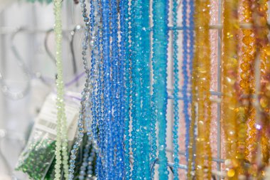 Beyaz arka planda çeşitli boyutlarda ve renklerde boncuklu kolyelerin canlı, yatay çizgisi