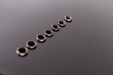 Metalik gitar halkalarından oluşan bir hat, karanlık bir arkaplana karşı dikey olarak dizilmiş, çaplarından daha büyük iç deliklerle.