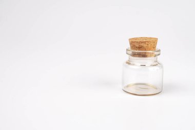 Kehribar sıvılı temiz cam şişe, gri zemin üzerine kurulmuş, hafifçe yana eğilmiş, görünür bir metin ya da damgalama yok, hatta kapalı bir ortamda ışık bile yok.