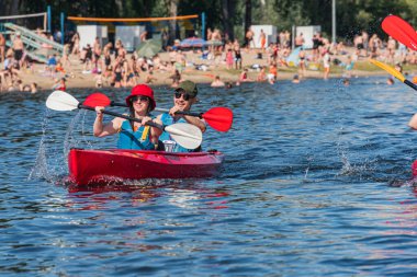 Bir gölde ya da nehirde üç kırmızı kanocu, biri önde aktif olarak kürek çekiyor, diğeri ortada duruyor, üçüncüsü arka planda kürek çekiyor Soft shad Kyiv, Ukrayna 07-12-2025