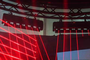 Gece kulübü, lazer şovu, DJ kabini kırmızı lazerler, mavi lazerler, geometrik desenler, hoparlörler aydınlatma platformları, canlı dinamik atmosfer, yüksek enerji, performans, siyah, kırmızı, mavi palet