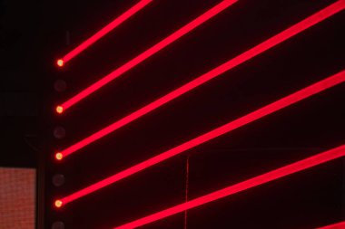 Kırmızı ve beyaz ışıklı konser sahnesi, yüksek kapasiteli mekan, büyük hoparlörler, kulis alanı, kırmızı ışık şebekesi, dramatik ışıklandırma düzeni, dinamik renk paleti kırmızı, beyaz, enerjik his