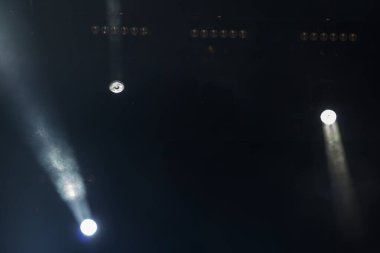 Uzun pozlama fotoğrafçılığıyla çekilen soyut sahne ışıklarının olduğu gece konseri sahnesi farklı yönlerde hareket eden ışık çizgilerini gösteren iki kareden oluşur.