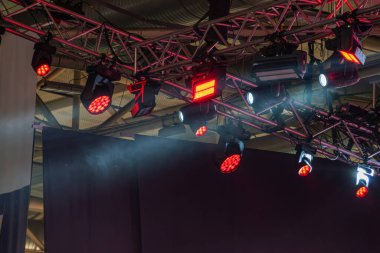 Aydınlatma armatürleri, açık kırmızı jeller, loş ışık altı zemin, sisli atmosfer, beyaz perde veya arka plan