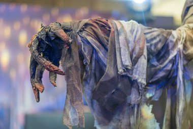 Tüylü elementleri olan çürüyen, yırtık pırtık bir insansı yaratık karanlık bir arkaplana karşı duruyor.