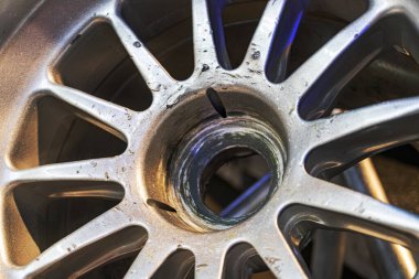 Metalik bir Formula 1 tekerleğinin yakın plan görüntüsü, daha hafif bileşenlerle çelişen karmaşık konuşma dizaynını gösteriyor