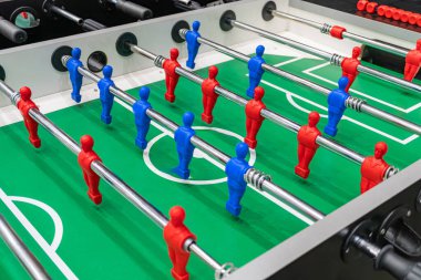 Kırmızı ve mavi oyuncak figürleriyle yeşil yüzey üzerinde sadeleştirilmiş kapalı futbol oyunu kurulumu, küçük bir futbol sahası statik düzenine benziyor Persp üzerinde olası makine veya ekipman gösterme önerir