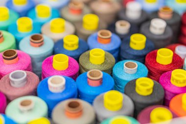 Tarafsız bir arkaplanda çok renkli iplik makaralarının dağılımı, estetik olarak memnun edici ama rastgele desenler halinde dizilmiş renkler kırmızılar, maviler, morlar, yeşiller, sarılar ve kahverengiler