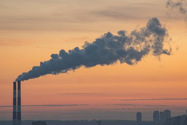 Elektrik santrali üzerinde gün batımı bacaları, turuncu ve mavi gökyüzü, yumuşak ışığa zıt endüstriyel yapı