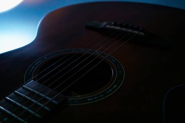 Koyu kahverengi akustik gitarın yakın plan görüntüsü iyi korunmuş metalik perdeler, iyi işçilik gösteren bulanık arka plan ve doğal ışıklandırma derinlik yaratır ve enstrümana odaklanır.