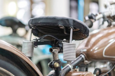 Klasik motosiklet koltuğu, siyah, pürüzsüz doku, hafif eğri, metalik süspansiyon sistemi veya ekipman, silindirik şekil, sarmal yaylar, potansiyel şok soğurma, yapay li ile iç mekan ayarları