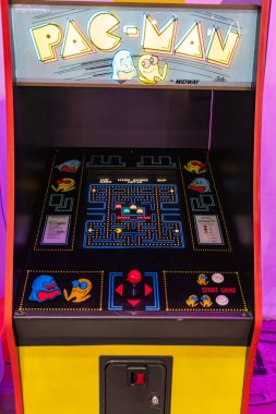 Mavi arka ışıklandırmalı parlak sarı Pac-Man atari makinesi, öne çıkan Pac-Man çıkartmaları, düğmeli kontrol paneli, kalın beyaz PAC-Man başlığı, Kyiv, Ukrayna - 8 Haziran 2025