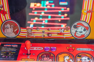 Kırmızı ve sarı Eşek Kong oyun makinesi, hayvan kafası illüstrasyonu, iki kontrol düğmesi, dairesel logo, renkli grafikler, kapalı mekan ayarı, muhtemelen Nintendo o Kyiv, Ukrayna - 7 Haziran 2025