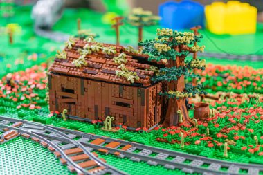 Lego minyatür sahnesinde yıpranmış kahverengi ahşap bir kulübe, yemyeşil bir kulübe ve küçük bir tren yolu Kyiv, Ukrayna - 7 Haziran 2025