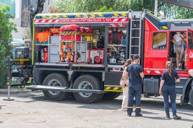 Beton bir zemine park etmiş büyük bir kırmızı itfaiye aracı, muhtemelen halka açık bir alanda merdivenler, hortumlar ve diğer kurtarma araçlarıyla donatılmış insanlar, Kyiv, Ukrayna - 7 Haziran 2025