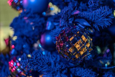 Kumarhanenin içindeki Noel ağacı, aşağıdan bakıldığında, yumuşak ışık altında mavi ve mor süslemelerle süslenmiş.