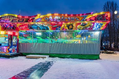 Karanlık gece panayır sahnesinde renkli, aydınlık bir atlı karlı zeminde sağlam bir yapı ve gölgelik vardı.