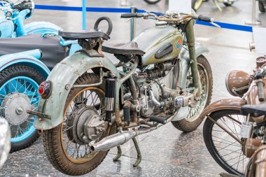 Antika Ukrayna KMZ Dnipro motosikleti müze benzeri antika motosikletlerle dolu geniş bir odada sergilenmektedir. Baskın bisiklet paslı mavi ve yeşildir, pos Kyiv, Ukrayna - 25 Ekim 2025