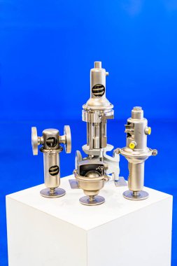 Görünür mekanik bileşenlere sahip üç endüstriyel metal parçasının özet koleksiyonu, silindirik şekiller, mavi gradyan aydınlatma ortamı ile nötr bir arkaplan