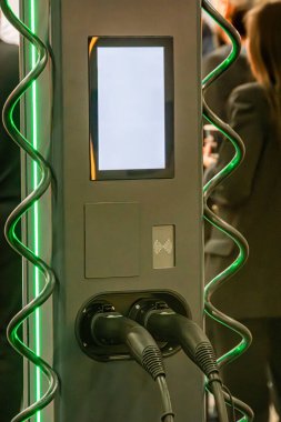 Yeşil aksanlı modern bir karanlık şarj istasyonu, çoklu kullanılmamış soketler, yumuşak ışıklandırma, ve ön grubunda bulanık bir figür