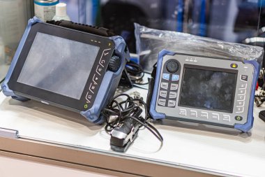 Tıbbi ya da çevresel testler için iki taşınabilir teşhis aracı, bir yüzeyde yan yana yerleştirilmiştir. Cihazların ekranları, kontrol düğmeleri ya da kadranları ve dayanıklı koruyucu kılıfları vardır.