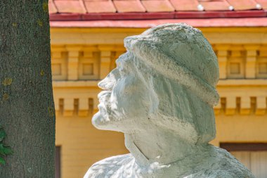 Geniş, bej renkli, geleneksel giyimli bir adam heykeli, halka açık bir yer, taş veya beton malzeme, uzun saç, sarı bina zemin, doğal Kyiv, Ukrayna - 11 Ağustos 2025