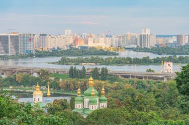Gündoğumunda Ukrayna şehir manzarası, yüksek görüş açısı, su kütlesi, kendine özgü kubbe yapısı, modern ve geleneksel mimarinin karışımı, sıcak aydınlatma, yani Kyiv, Ukrayna - 23 Ağustos 2025