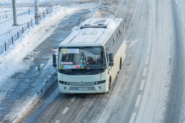 Geniş, beyaz otobüslü, karlı bir yol. İçerideki insanlar karanlık pencerelerden içeri giriyor. Öndeki görünür metin, ıslak Kyiv, Ukrayna 'nın karışık açısından dolayı okunamıyor.