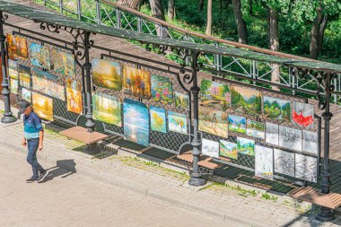 Kyivs Artists Sokak 'taki açık hava sanat sergisinde demir parmaklıklı küçük bir çardak. Çerçevelenmiş çeşitli eserler, muhtemelen fotoğraflar ya da baskılar sergileniyor. Doğal Gün Işığı Kyiv, Ukrayna - 23 Temmuz 2025