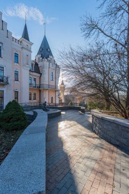 Alacakaranlık sırasında tarihi Kyiv Akademik Kukla Tiyatrosu, sivri kemerli pencereli pembe cephe ve dik kule çitleri düzgünce budanmış, yaprakları değiştiren ağaç, tuğla pa Kyiv, Ukrayna - 13 Aralık 2025