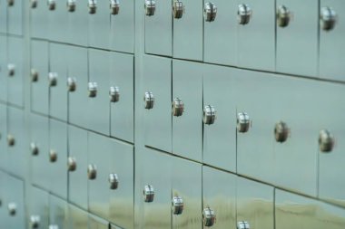 Nötr bir duvara monte edilmiş dikey kiralık kasaların koleksiyonu 3 büyük 1 küçük posta kutusu, gümüş tonlu saplar ve kilitler, metin ya da marka yok, hatta ışıklandırma, kapalı alan ayarları, açılı