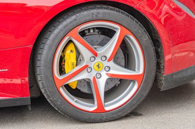 Kırmızı spor araba tekerleği ve yan panelin yakın plan görüntüsü, farklı dizaynlı gümüş alaşımlı jantlar içeriyor. Lastik nispeten yeni ve sarı etiketli Kyiv, Ukrayna 10-12-2024