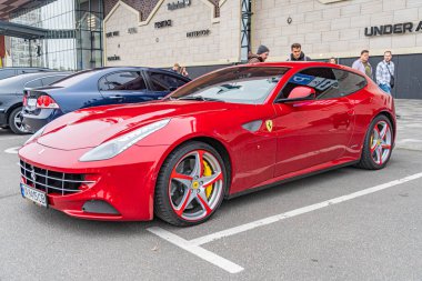 Ferrari 'ye benzeyen kırmızı bir spor araba, gündüz vakti bir şehir caddesinde park edilir. Yüksek performanslı aracın gösterişli tasarımı, belirgin hava girişleri, siyah whe Kyiv, Ukrayna 10-12-2024