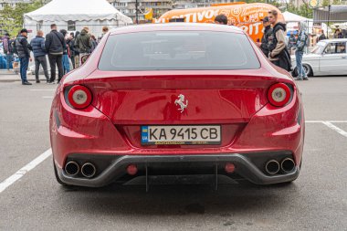 Bir etkinlik ya da toplanma sırasında şehir caddesinde park etmiş bir Ferrari 'nin gizli bir fotoğrafı. Spor arabanın kendine özgü yuvarlak stop lambaları ve oval bir amblemi var. Kyiv, Ukrayna 10-12-2024