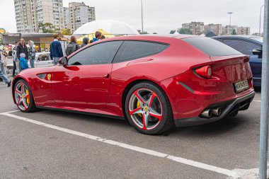 Asfalt bir zemine park etmiş kırmızı bir spor arabanın yan görüntüsü, muhtemelen kentsel bir çevrede, araba aerodinamik tasarım özelliklerine sahip, siyah ve kırmızı beş dilli alaşım wh Kyiv, Ukrayna 10-12-2024