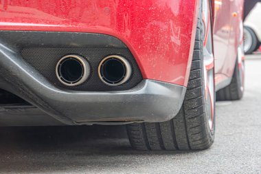 Aerodinamik detaylara sahip kırmızı bir spor araba, kentsel bir çevrede ıslak bir asfalt üzerine park edilmiş beş dilli alaşımlı fiber tekerlekleri ve derin basamaklı ti Kyiv, Ukrayna 10-12-2024