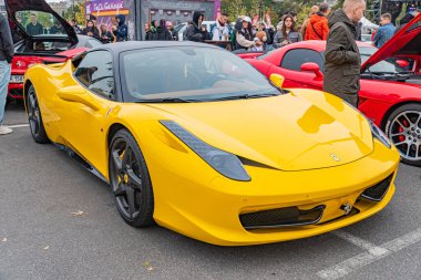 Canlı sarı bir spor araba bir etkinlikte kaldırıma park edilmiş, gösterişli bir tasarım, geniş hava girişleri, açılı farlar ve çok dilli alaşımlı tekerlekler 10-12-2024 Ukrayna, Kyiv 'i geçiyor.