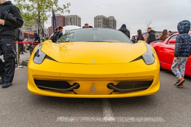 Canlı sarı bir spor araba, bir çerçeveye açıyla hakim olmak, insanlarla çevrili ve kısmen Kyiv, Ukrayna 10-12-2024 'ü izleyen açık hava otomotiv etkinliğinin veya serginin odak noktasıdır.