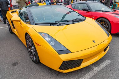 Açık hava parkına park etmiş parlak sarı bir Lamborghini. Bu da açık hava olayına işaret ediyor. Arabanın keskin açıları, geniş hava girişleri ve Ukrayna, 10-12-2024 arazi girişleri var.