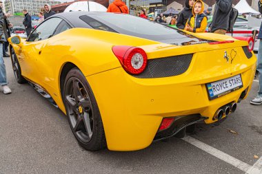 Ön sağ tarafında hasar olan sarı bir Ferrari halka açık bir caddede park halinde, arka planda bulanık yayalar Kyiv, Ukrayna 10-12-2024