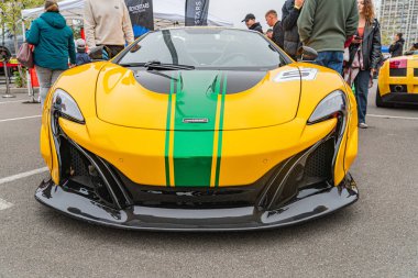 Yeşil ve siyah yarış çizgilerine sahip canlı sarı bir spor araba asfalt bir yüzeye park edilmiştir. Parlak aerodinamik tasarım, büyük ızgara ve eşsiz tekerlek tasarımı şekeri Kyiv, Ukrayna 10-12-2024