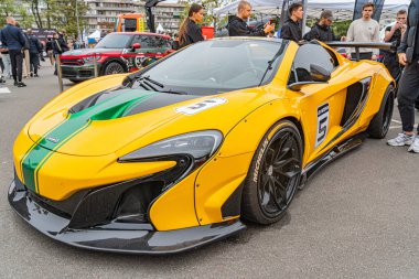 Yeşil aksanlı canlı sarı bir yarış arabası, muhtemelen bir şehir etkinliğinin parçası olan bir galeride ya da sergide sergileniyor. 5 rakamı Ukrayna, Kyiv, 10-12-2024 tarafında belirgin bir şekilde görülüyor.