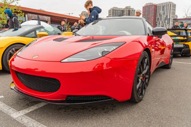 Kırmızı, yüksek performanslı, lüks bir spor araba şehir merkezinde park halinde, muhtemelen bir alışveriş alanı yakınında bir sokak ya da otopark bulutlu gökyüzü Kyiv, Ukrayna 10-12-2024