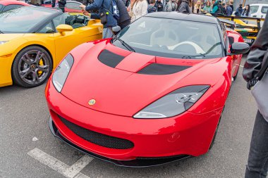 Kırmızı bir spor araba bir otomobil fuarında sergileniyor, aerodinamik tasarım sergileniyor, güçlü motor hava girişi tarafından ima ediliyor, hız performansı için çok dilli tekerlekler, I Kyiv, Ukrayna 10-12-2024