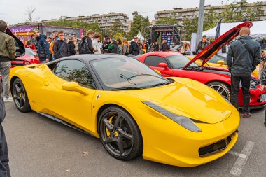 Canlı sarı bir spor araba, muhtemelen Lamborghini Gallardo, asfalt bir zeminde köşegen olarak park edilmiştir. Bir halk etkinliğinde arka planda insanlar vardır veya Ukrayna, Kyiv, 10-12-2024 'e erişimi vardır.