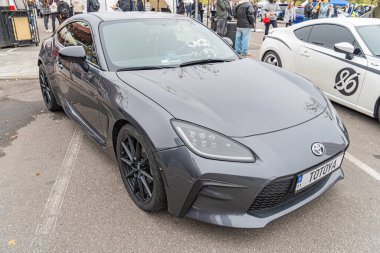 Gösterişli, yüksek performanslı bir araba, muhtemelen bir gösteri veya etkinlikte, agresif bir tasarım, koyu renk kaplama, çok dilli tekerlekler, ve marka logosu belirgin bir şekilde Kyiv, Ukrayna 10-12-2024