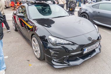 Şehir sokağında agresif bir tasarımı olan modern siyah spor bir coupe büyük alaşımlı tekerlekleri, düşük profilli lastikleri ve kendine özgü marka kimliği olan Kyiv, Ukrayna 10-12-2024