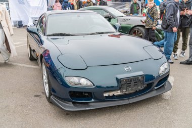 Koyu mavi bir Nissan GT-R spor araba kapalı bir otomobil etkinliğinde sergileniyor. Araç LED farlar, büyük girişler, aerodinamik şekiller ve parlak bir Kyiv, Ukrayna 10-12-2024