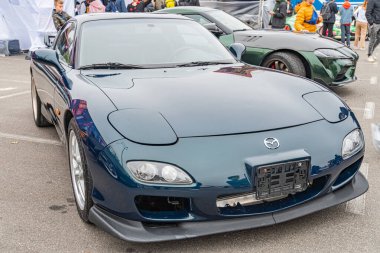 Koyu mavi bir Nissan spor arabası, muhtemelen bir otomotiv etkinliği olan asfalt yüzeyde belirgin bir açıyla sergilenmektedir. Pürüzsüz ve mavi renkler Kyiv, Ukrayna 10-12-2024 vurgulanmıştır.