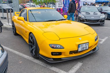 Pürüzsüz sarı spor bir araba, açılı farlar, fonksiyonel jantlar ve arka kanat spoiler, Ukrayna, Kyiv, 10-12-2024 'te park edilmiş.